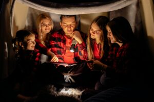 Caucasian family. Dad reads the story sitting in a teepee, reading stories