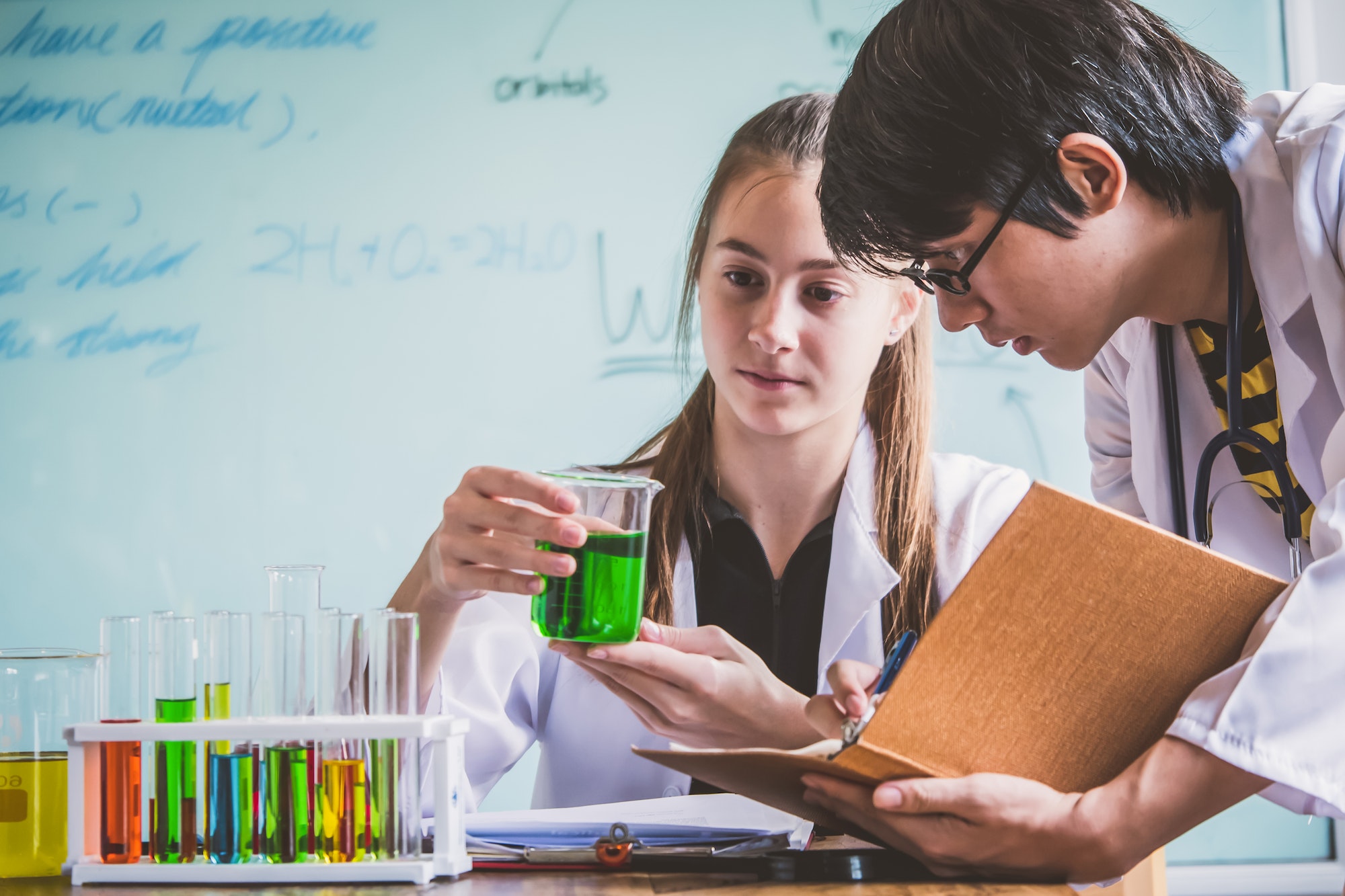 Couple of students working at chemistry class. Education concept