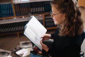 Teenager girl reading a book in the library