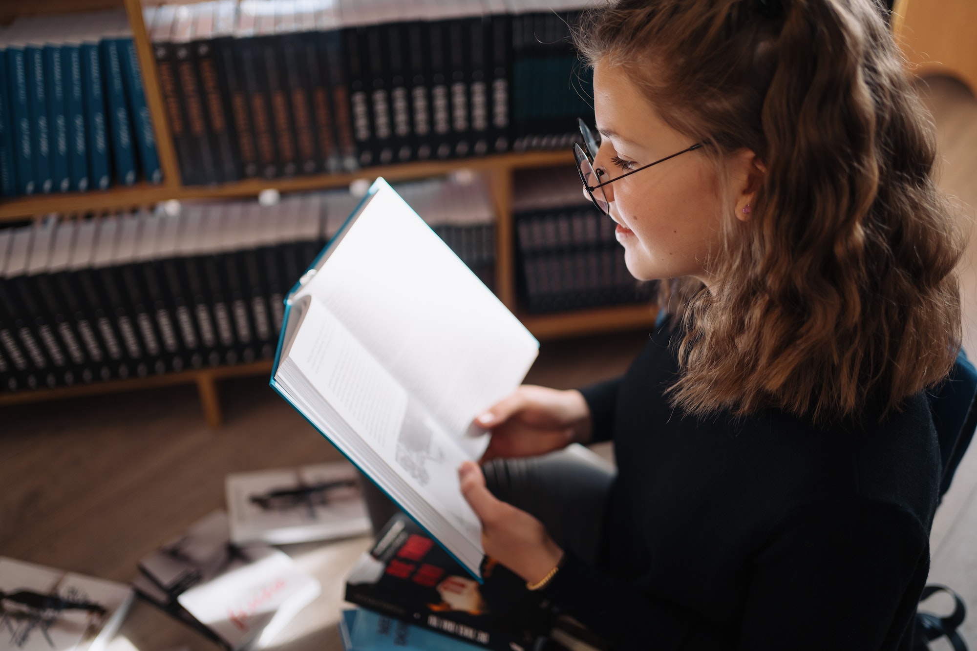 Teenager girl reading a book in the library